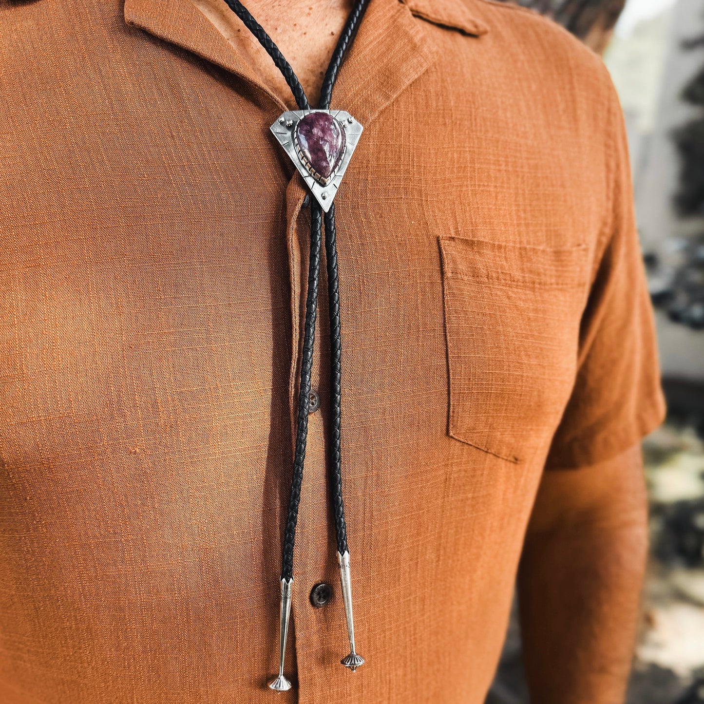 photo of a mans chest wearing rust colored shirt and a triangle silver lepidolite bolo tie