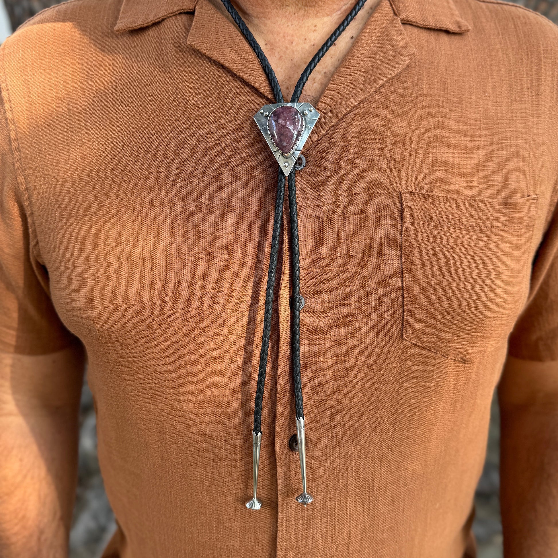 photo of a mans chest wearing rust colored shirt and a triangle silver lepidolite bolo tie