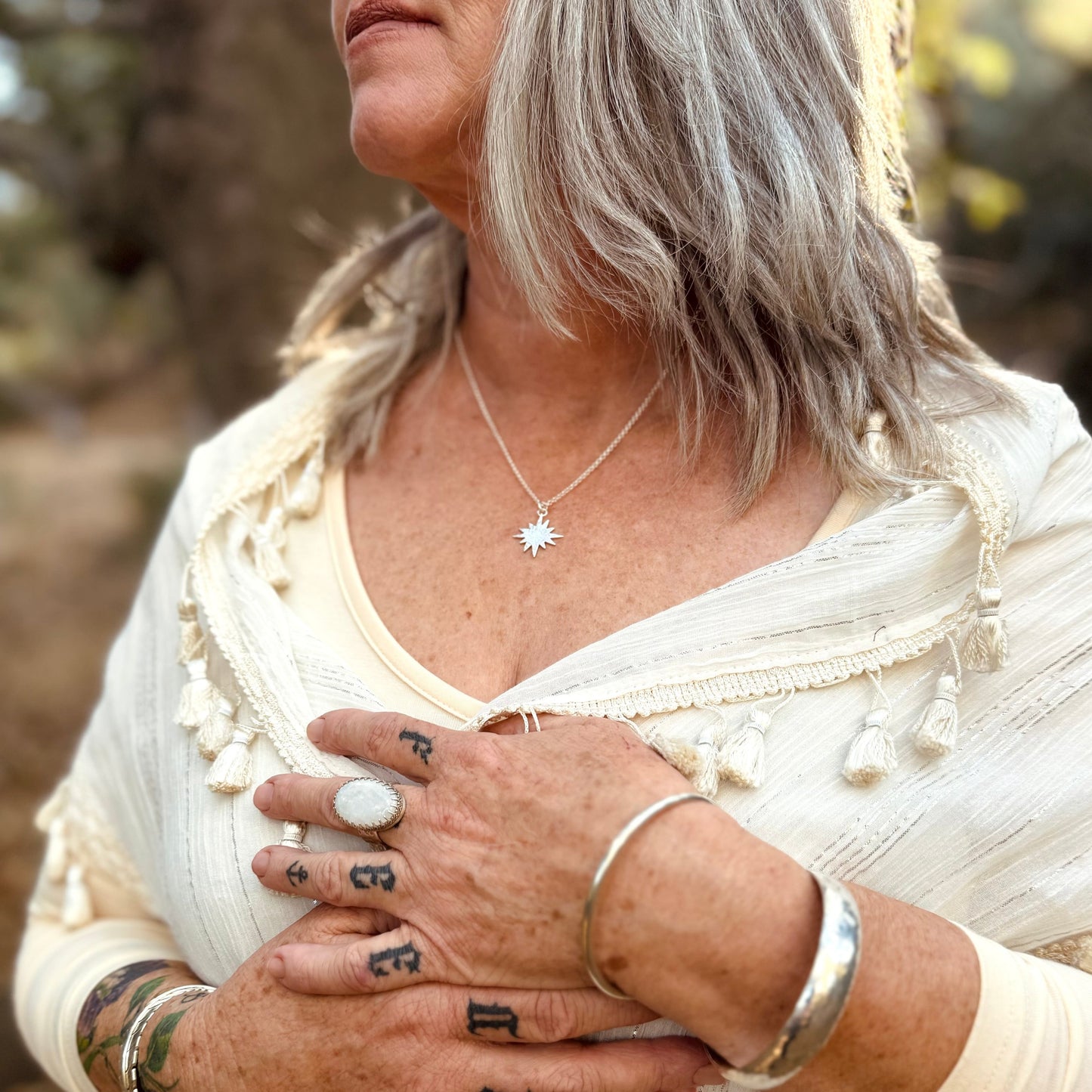 silver sun flare necklace on a lady wearing white in the forest