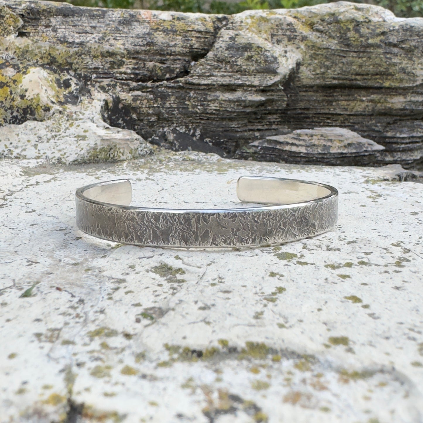 photo of a thick silver cuff bracelet with a rustic hammered texture