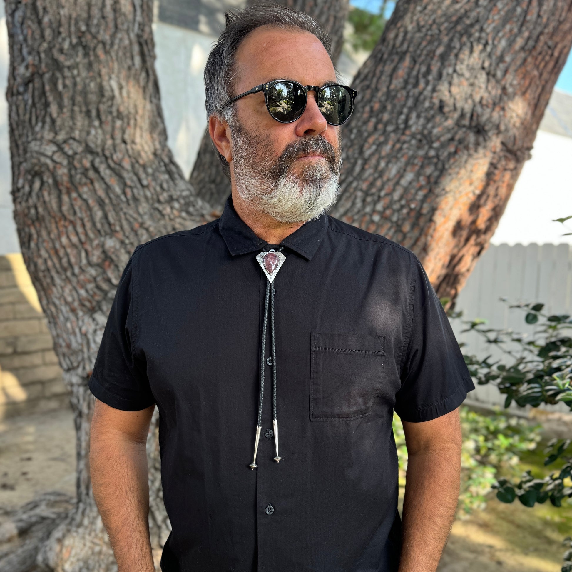 photo of a mans chest wearing black collared shirt and a triangle silver lepidolite bolo tie 