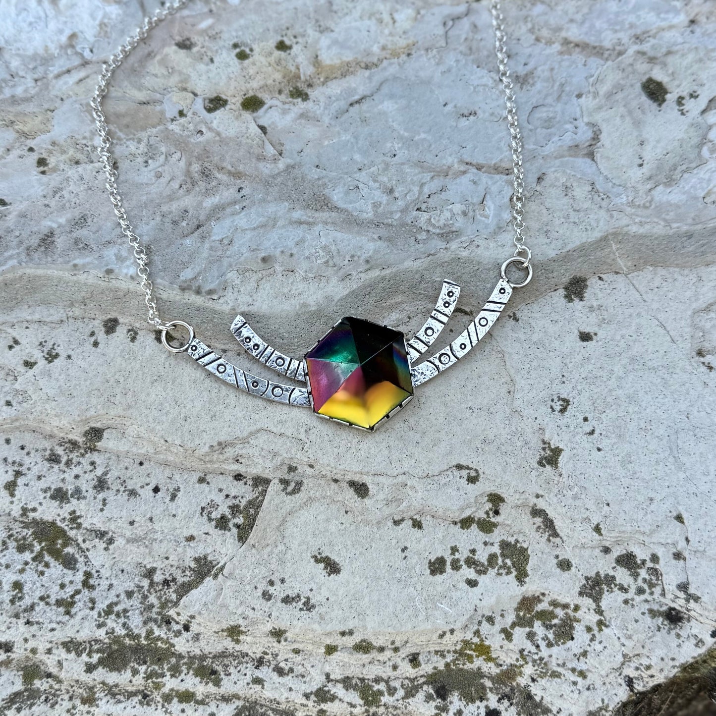 Necklace with a colorful pendant on a textured stone surface