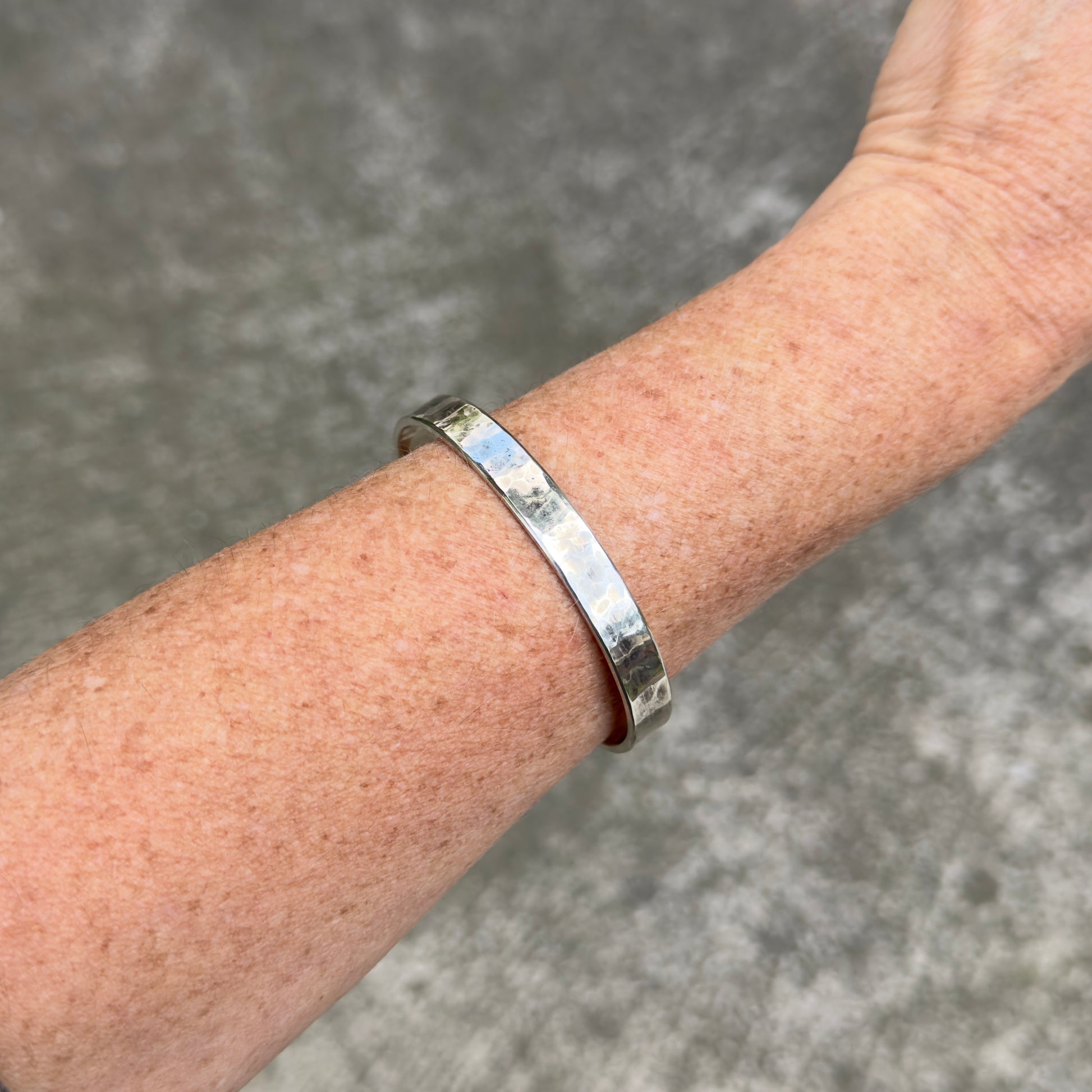 photo of a thick silver cuff bracelet with a hammered texture