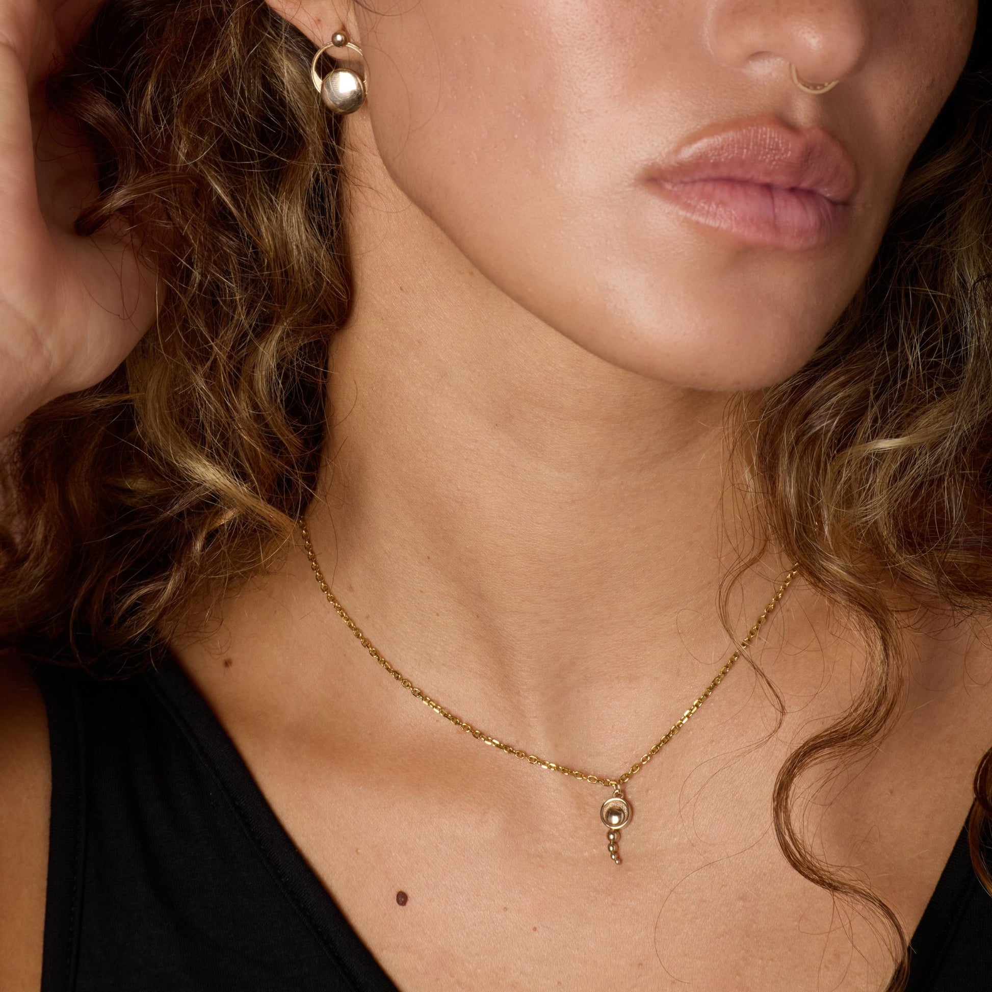 Close-up of a woman wearing a gold-toned necklace and earrings.