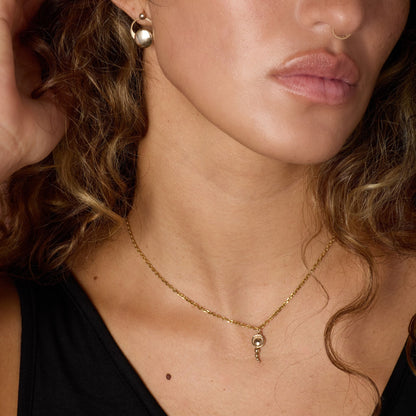 Close-up of a woman wearing a gold-toned necklace and earrings.