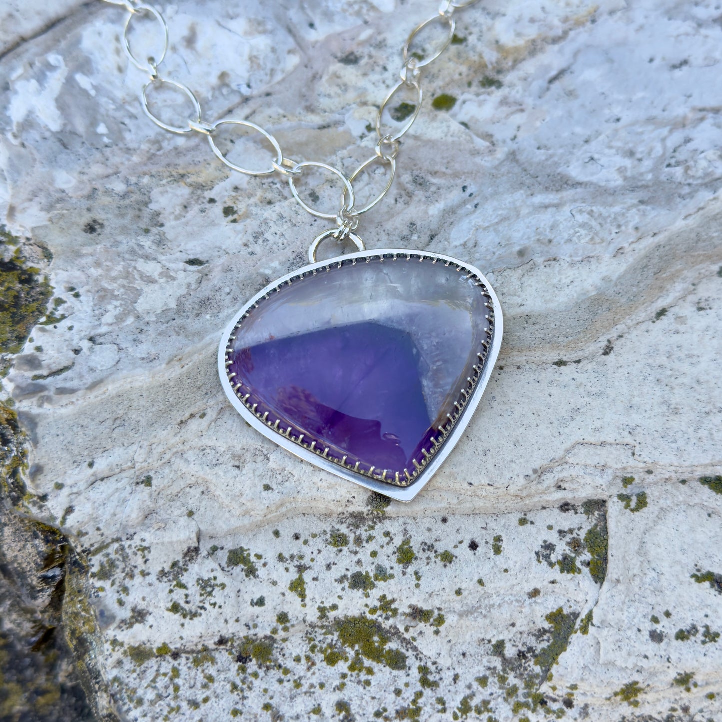 picture of a silver amethyst necklace on a rock 