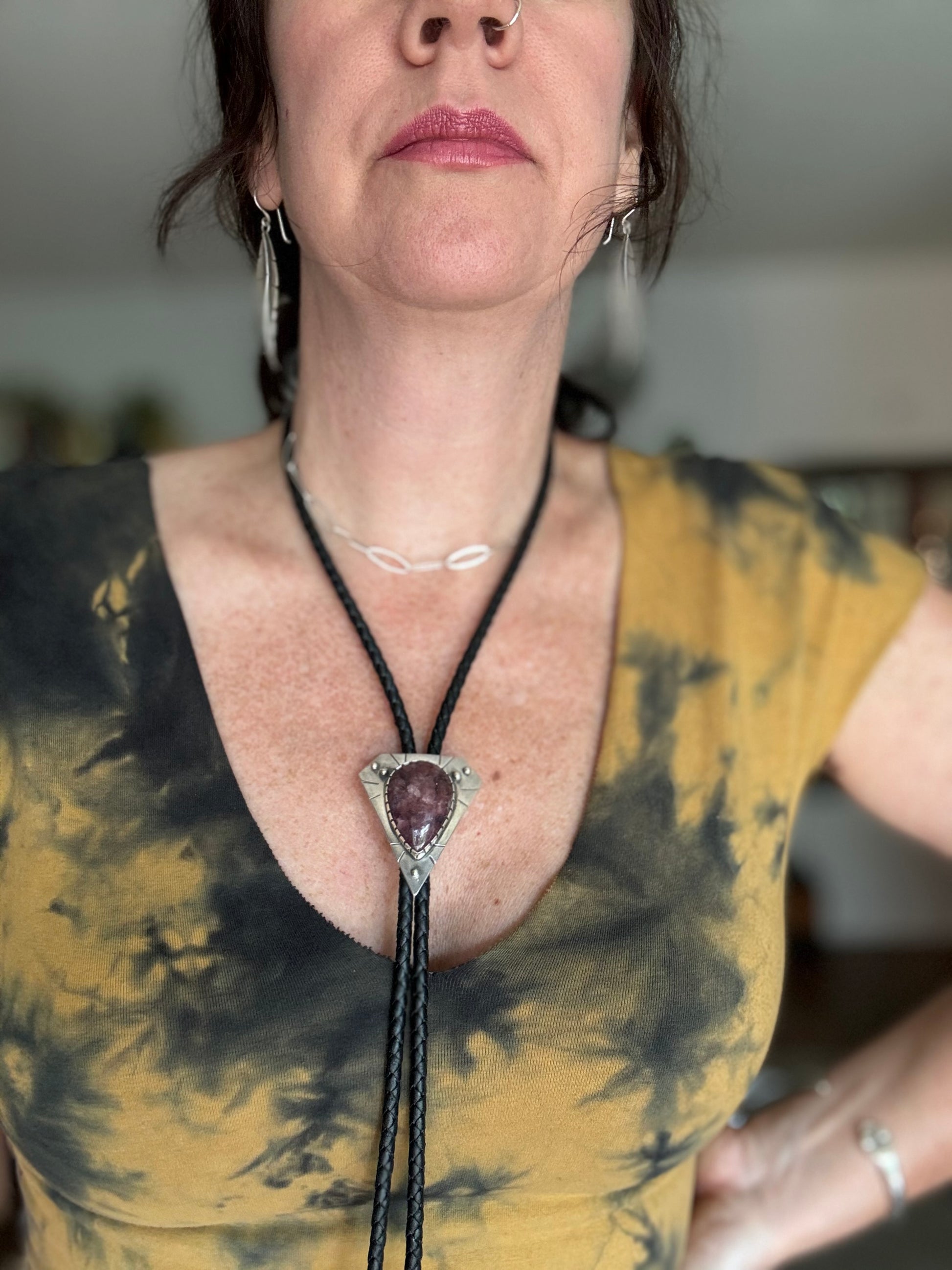 photo of a woman wearing a silver lepidolite bolo tie and yellow tie died top and cowboy hat