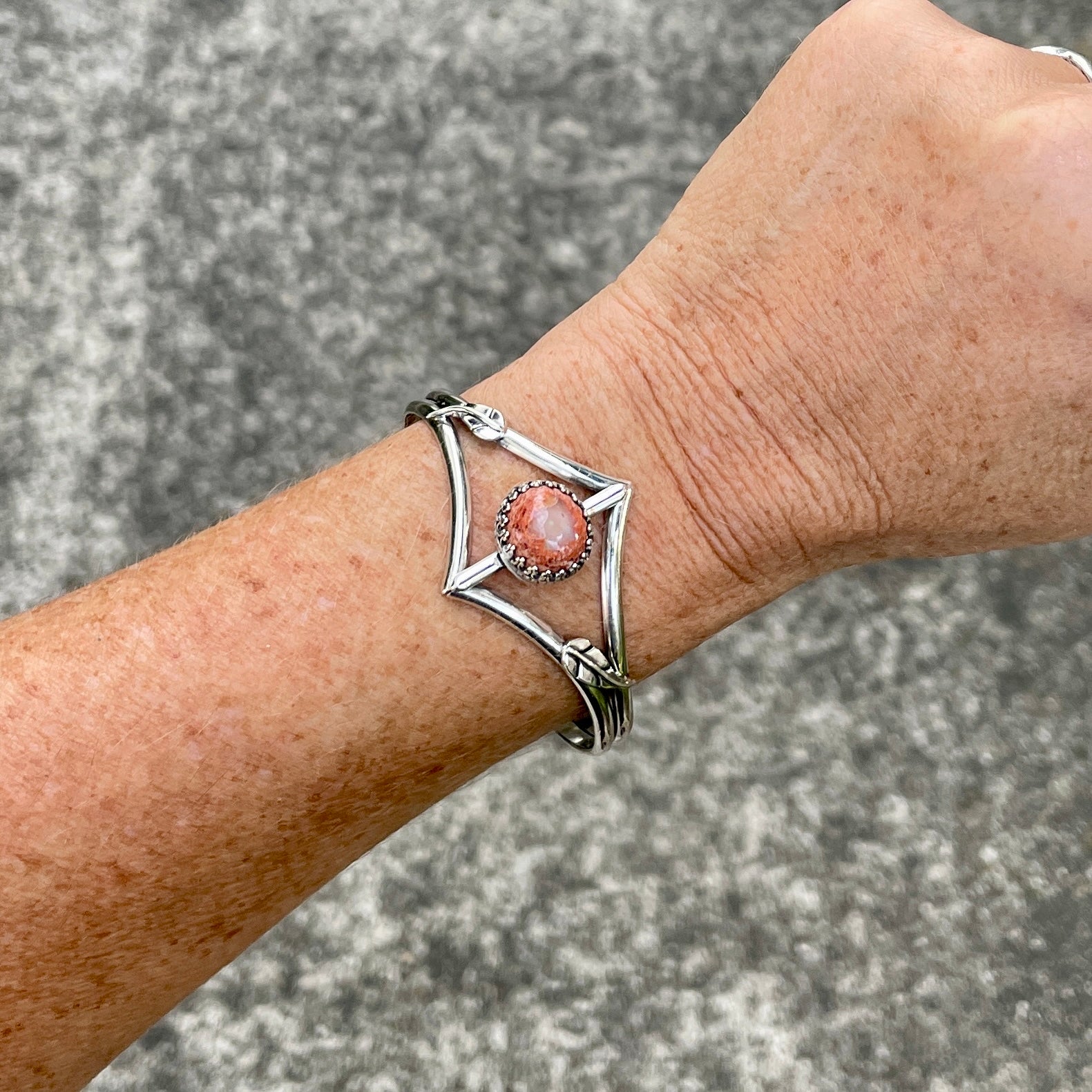 photo of a woman's forearm waering an orange cantera opal and silver cuff bracelet with leaves