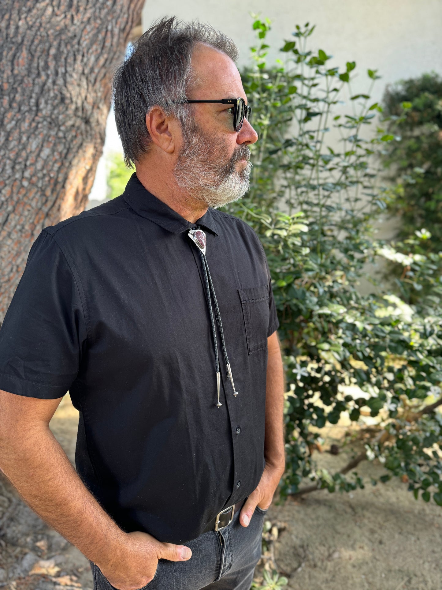 photo of a mans chest wearing black collared shirt and a triangle silver lepidolite bolo tie 