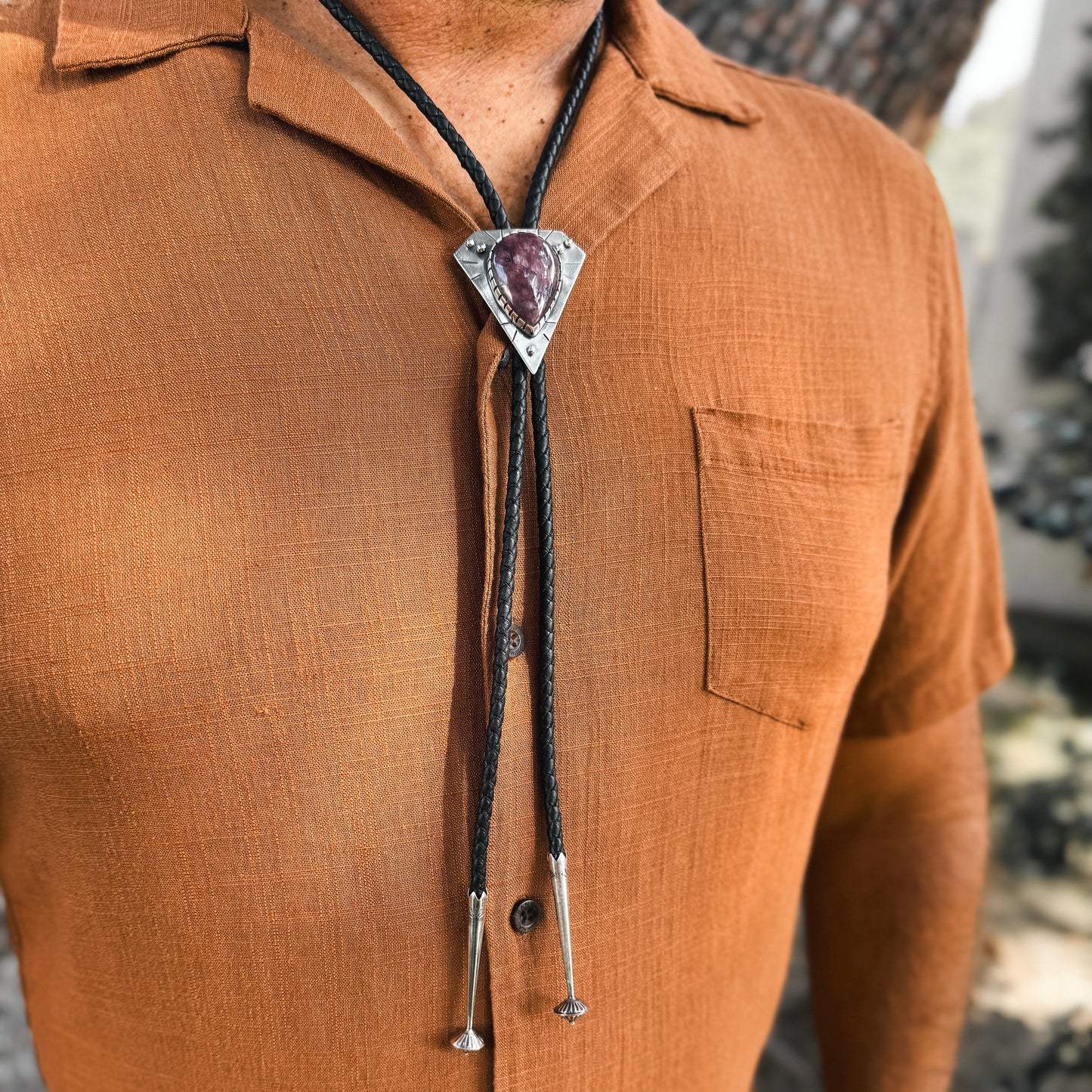 photo of a mans chest wearing rust colored shirt and a triangle silver lepidolite bolo tie 