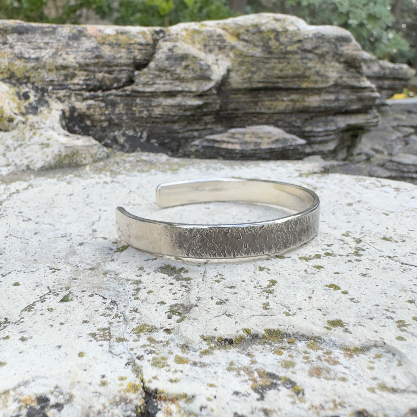 photo of a thick silver cuff bracelet with a rustic hammered texture