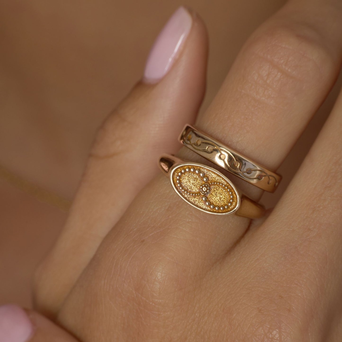 Gold-toned  ring with infinity design on a finger against a neutral background