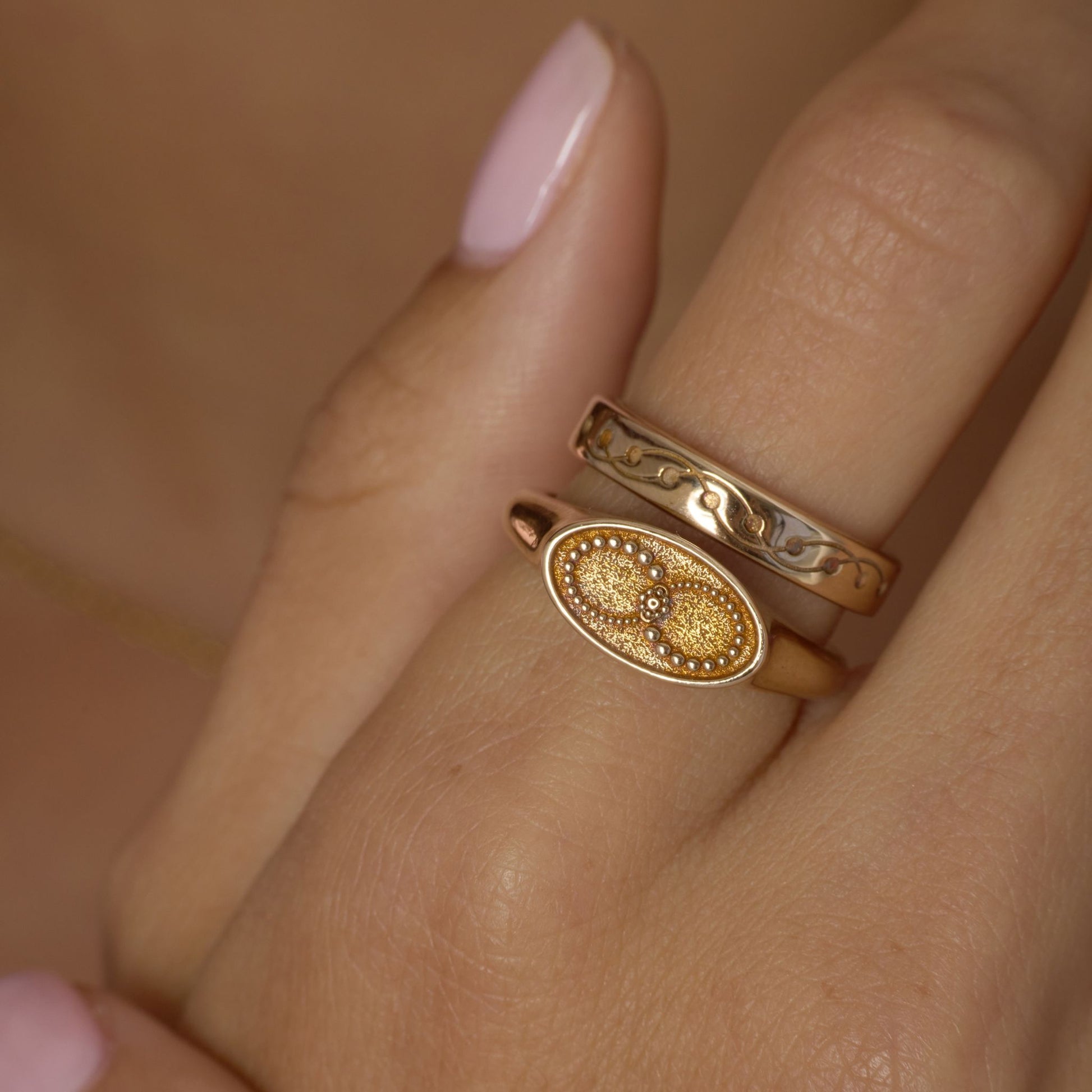 Gold-toned  ring with infinity design on a finger against a neutral background