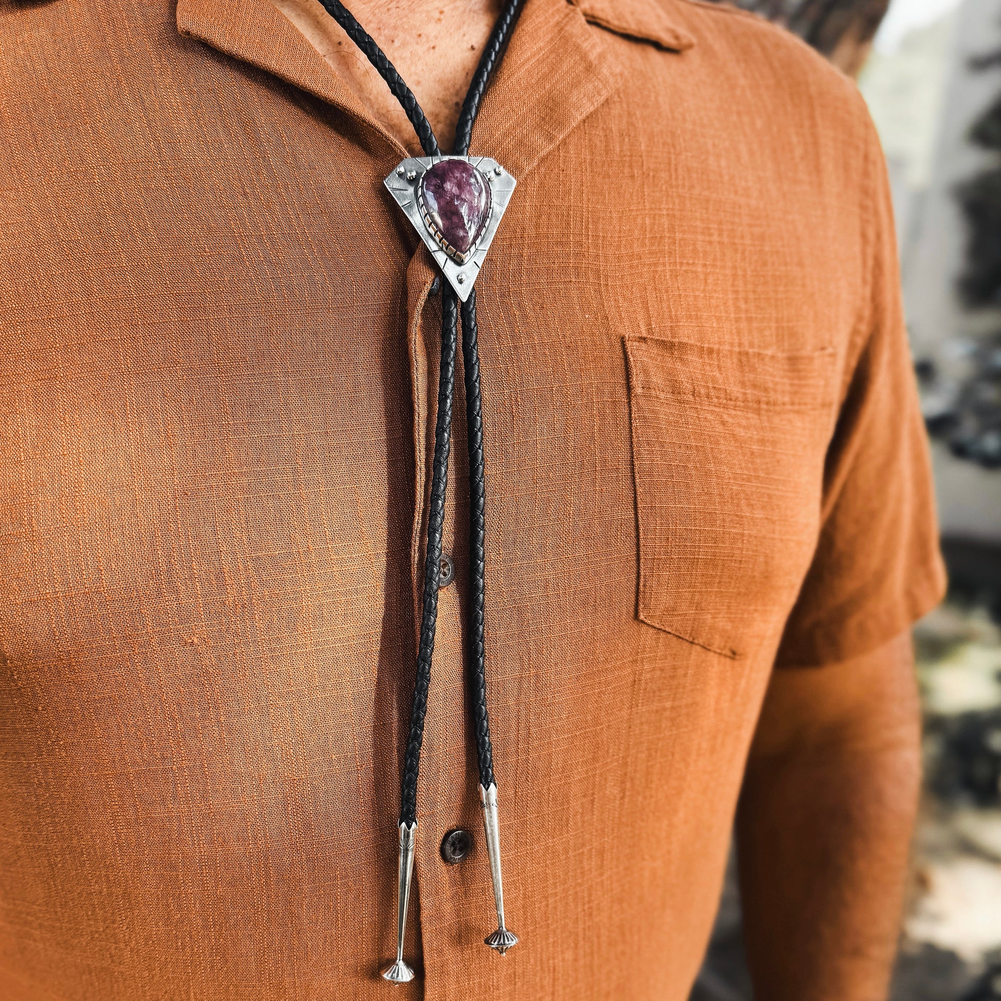 photo of a mans chest wearing rust colored shirt and a triangle silver lepidolite bolo tie 