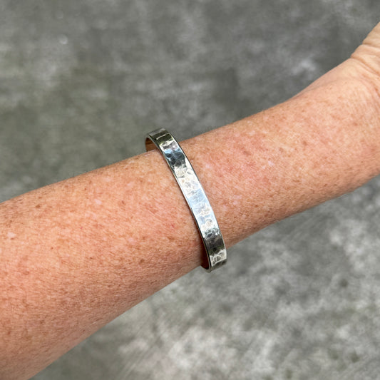 photo of a thick silver cuff bracelet with a hammered texture