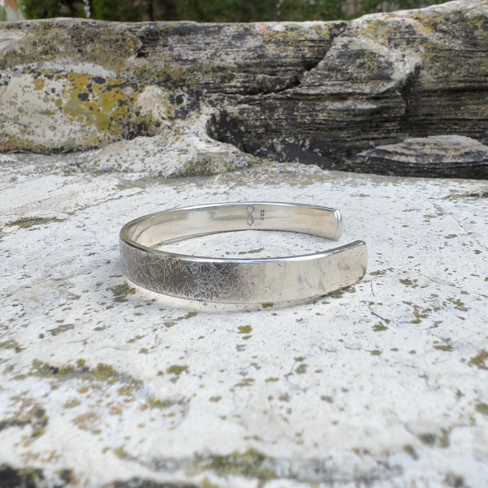 photo of a thick silver cuff bracelet with a rustic hammered texture