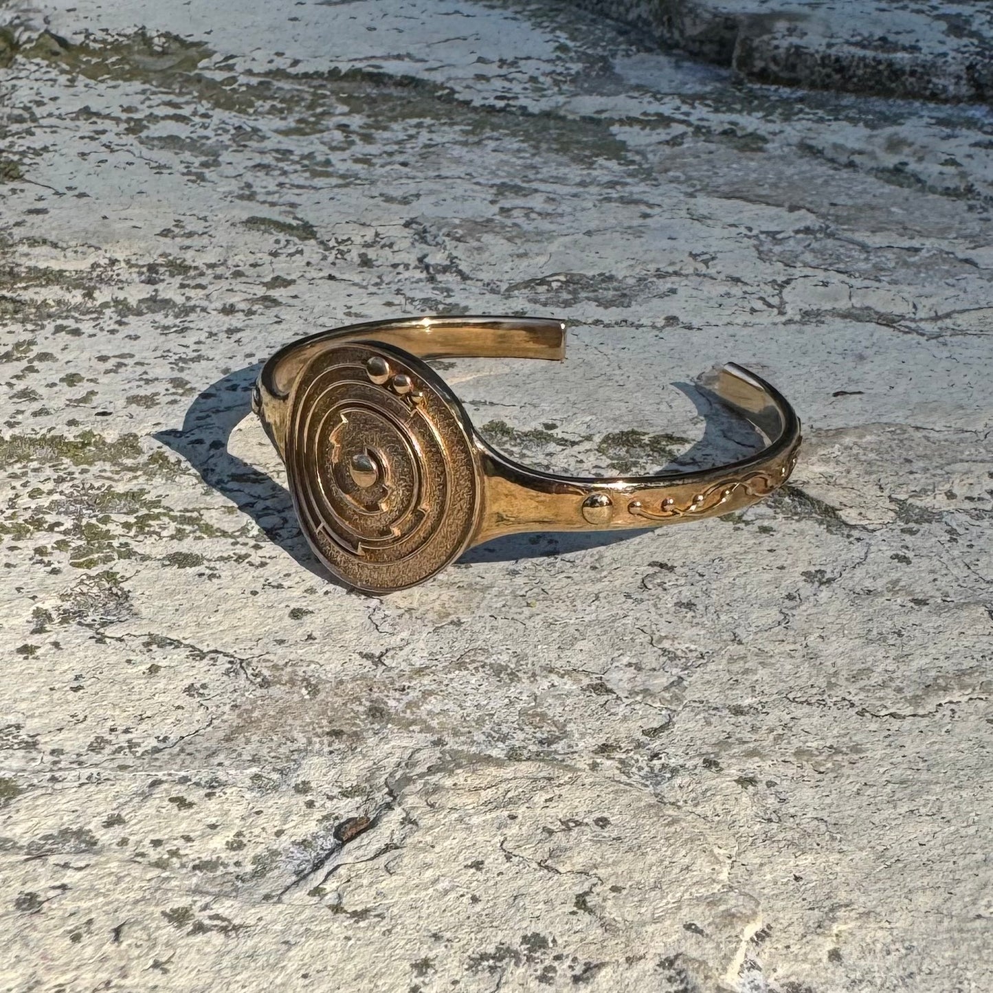 Bronze cuff bracelet on a textured stone surface