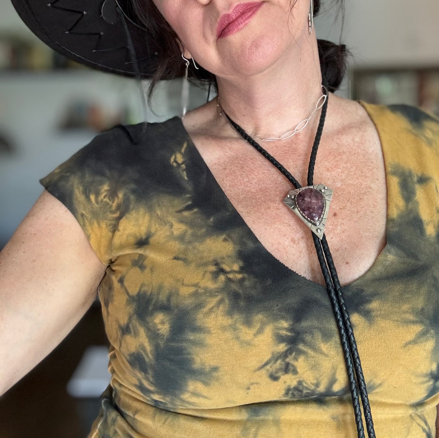 photo of a woman wearing a silver lepidolite bolo tie and yellow tie died top and cowboy hat