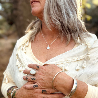 silver sun flare necklace on a lady wearing white in the forest 